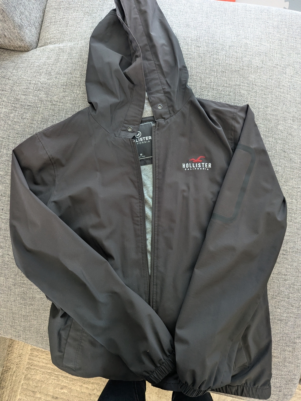 Hollister Men's Black Hooded Rain Jacket with Red Logo